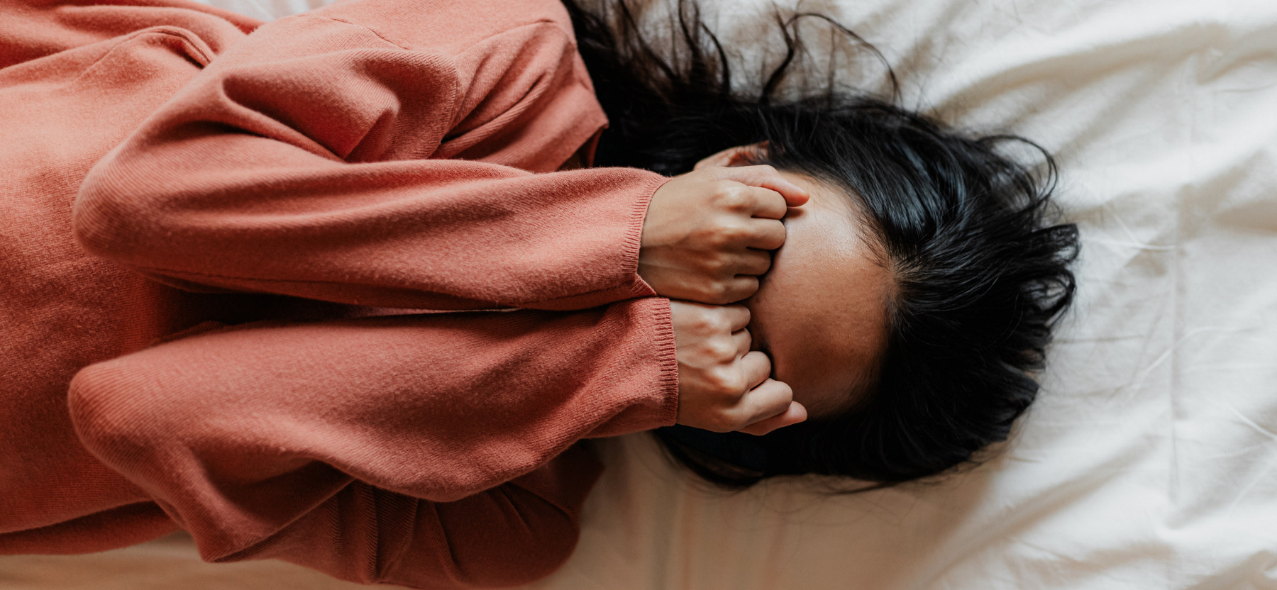 femme sur son lit avec les mains sur les yeux