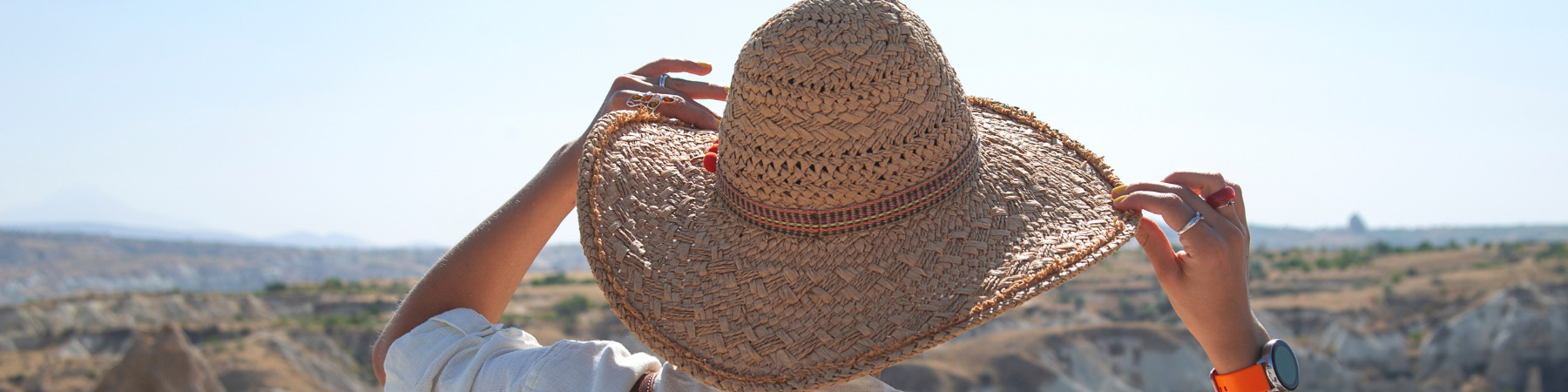 une femme de dos avec un chapeau en pleins soleil