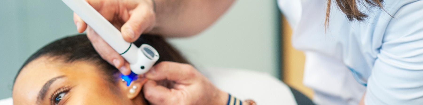 un médecin qui ausculte l'oreille d'une patiente